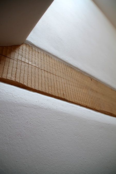 Sägespuren an Holzbalken mit Lehmputzoberfläche