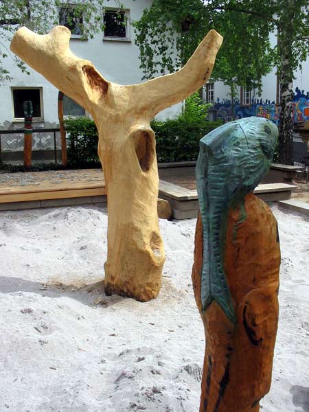 Die Holzskulpturen aus Robinie und der Kletterbaum aus Eiche im Sandbereich des Spielplatzes.